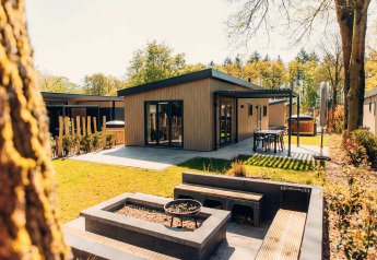 Lodge Loevestein Deluxe en el parque Veluwe de Bosgraaf, Países Bajos, con terraza y zona de fuego.