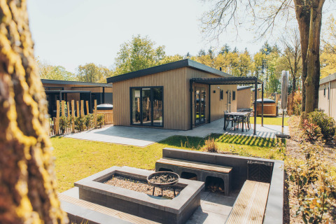 Loevestein Deluxe lodge at Veluwe park de Bosgraaf, Netherlands, with patio, outdoor dining, and firepit.