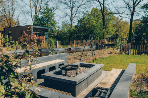 Outdoor seating area with fire pit at Loevestein Deluxe lodge in Veluwe park de Bosgraaf, Netherlands.