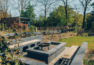 Outdoor seating area with fire pit at Loevestein Deluxe lodge in Veluwe park de Bosgraaf, Netherlands.