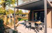 Outdoor terrace with dining table at Loevestein Comfort lodge in Veluwe park de Bosgraaf, Netherlands.