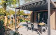 Terraza con mesa y sillas en el lodge Loevestein Comfort en el parque Veluwe de Bosgraaf, Países Bajos.