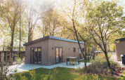 Lodge Loevestein avec jacuzzi extérieur, entouré d’arbres et terrasse moderne sous le soleil éclatant.