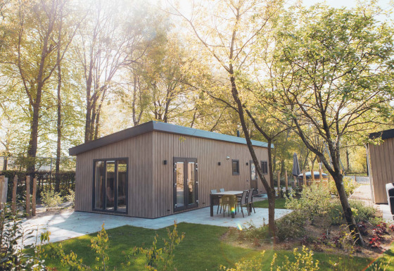 Lodge Loevestein avec jacuzzi extérieur, entouré d’arbres et terrasse moderne sous le soleil éclatant.