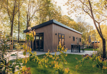 Un moderno lodge in legno Loevestein nel Veluwe park de Bosgraaf, Paesi Bassi, con patio e verde attorno.