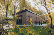 Un moderno lodge in legno Loevestein nel Veluwe park de Bosgraaf, Paesi Bassi, con patio e verde attorno.