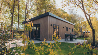 Et moderne træhus ved Veluwe park de Bosgraaf i Nederlandene med udendørs spiseplads og grønne omgivelser.