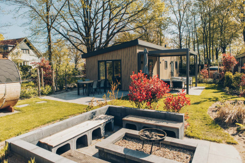 Area esterna della lodge Loevestein Deluxe al parco Veluwe de Bosgraaf, Paesi Bassi, con terrazza e braciere.