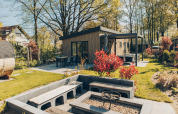 Area esterna della lodge Loevestein Deluxe al parco Veluwe de Bosgraaf, Paesi Bassi, con terrazza e braciere.