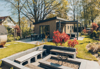 Area esterna della lodge Loevestein Deluxe al parco Veluwe de Bosgraaf, Paesi Bassi, con terrazza e braciere.