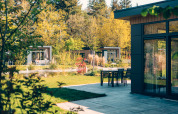 Moderne Lodges und Terrasse im Veluwe Park de Bosgraaf, umgeben von grüner Natur und Bäumen in den Niederlanden.