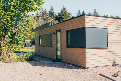 Moderno lodge in legno chiamato 'Cannenburch' nel Veluwe park de Bosgraaf, Paesi Bassi, tra alberi e natura.