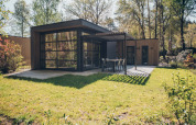 Lodge moderno Bosvilla Comfort al Veluwe park de Bosgraaf con ampie vetrate, terrazza e giardino verde.