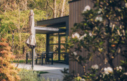 Terrazza con tavolo, sedie e ombrellone chiuso presso Bosvilla Comfort al parco Veluwe de Bosgraaf, Paesi Bassi.