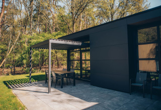 Udendørs terrasse ved Bosvilla Comfort-lodge i Veluwe park de Bosgraaf, Holland, omgivet af skov.