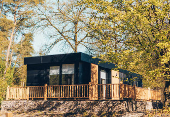 Moderne lodge Valkhof met hottub, omgeven door groen en zonlicht, perfect voor ontspannen in de natuur.