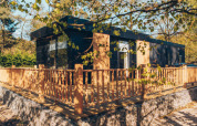Moderne lodge med træterrasse og hegn, omgivet af skov, ved Veluwe park de Bosgraaf i Nederlandene.