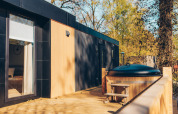 Terraza exterior con jacuzzi en la cabaña Valkhof met Hottub del parque Veluwe de Bosgraaf, Países Bajos.