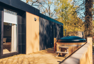 Terraza exterior con jacuzzi en la cabaña Valkhof met Hottub del parque Veluwe de Bosgraaf, Países Bajos.