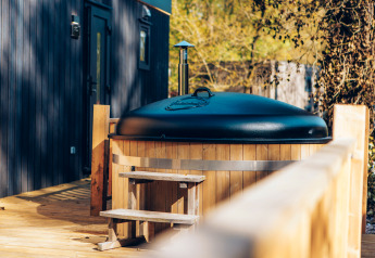 Outdoor wooden hot tub with black lid on deck at Valkhof met Hottub, Veluwe park de Bosgraaf, Netherlands.