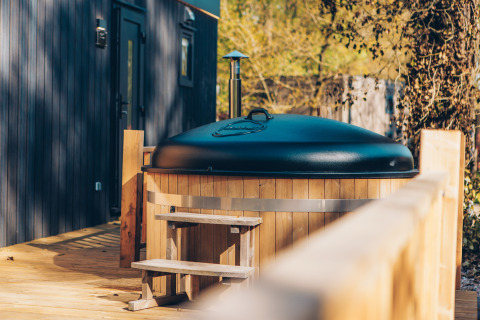Bañera de hidromasaje de madera con tapa negra en la terraza de Valkhof met Hottub, Veluwe park de Bosgraaf, Países Bajos.