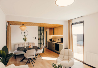 Modern lodge living and kitchen space with natural light at Valkhof met Hottub, Veluwe park de Bosgraaf, Netherlands.