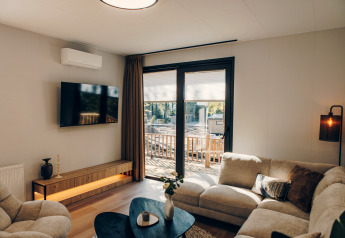 Cozy living room at Valkhof met Hottub lodge in Veluwe park de Bosgraaf with modern decor and large windows.