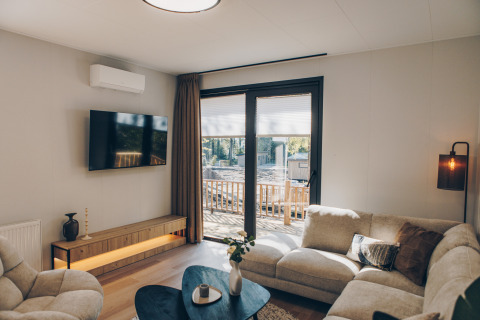 Knusse woonkamer in Valkhof met Hottub-lodge bij Veluwe park de Bosgraaf met modern interieur en grote ramen.