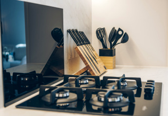 Modern kitchen countertop with gas stove, knife block, and utensils at Valkhof met Hottub in Veluwe park de Bosgraaf.
