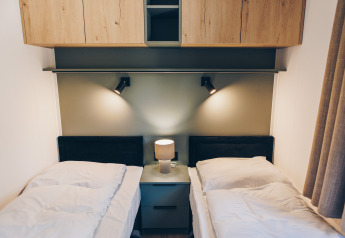Moderne lodgekamer met twee eenpersoonsbedden en nachtkastje in Valkhof met Hottub, Veluwe park de Bosgraaf, Nederland.