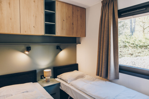 Dormitorio moderno con dos camas individuales, armarios de madera y ventana en Valkhof met Hottub, Veluwe.