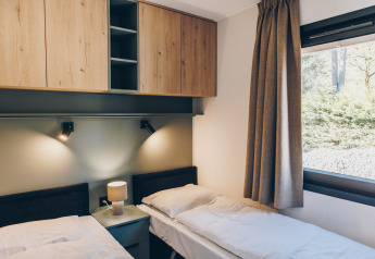 Camera da letto moderna con due letti singoli, armadi in legno e finestra al Valkhof met Hottub, Veluwe.