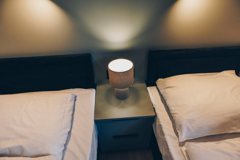 Dos camas individuales con sábanas blancas y una lámpara de noche en Valkhof met Hottub en Veluwe park de Bosgraaf, Países Bajos.
