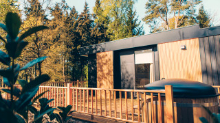Moderne Lodge Valkhof mit Whirlpool und Holzterrasse inmitten von Bäumen im Veluwe Park de Bosgraaf, Niederlande.
