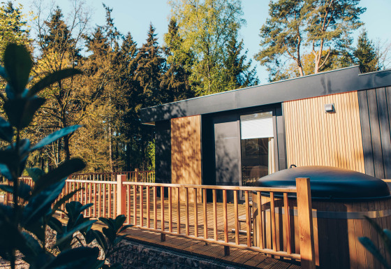 Lodge Valkhof moderno con jacuzzi y terraza de madera, rodeado de árboles en Veluwe Park de Bosgraaf, Países Bajos.