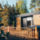 Modern Valkhof lodge with hot tub and wooden deck, surrounded by trees at Veluwe Park de Bosgraaf, Netherlands.
