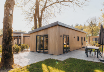Cabaña moderna de madera en Loevestein Lodge con terraza exterior y muebles de jardín entre árboles.