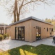 Moderne træhytte ved Loevestein Lodge med store vinduer, terrasse og havemøbler i naturskønne omgivelser.