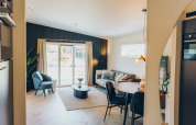Acogedora sala de estar moderna en un alojamiento glamping, con sofá, mesa de comedor y ventanales.