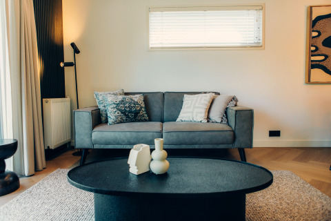 Modernes Wohnzimmer in einer Glamping-Unterkunft mit grauem Sofa, Couchtisch und dekorativen Kissen.