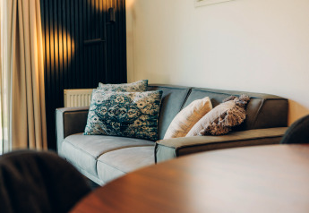 Canapé moderne avec coussins décoratifs dans un hébergement glamping, ambiance chaleureuse et élégante.