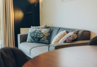 Canapé moderne avec coussins décoratifs dans un hébergement glamping, ambiance chaleureuse et élégante.