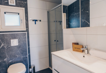 Moderne badkamer bij een glamping-accommodatie met douche, toilet, wastafel, spiegel en stijlvolle inrichting.