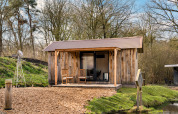 Casa di legno chiamata 'Barn' al campeggio Si-Es-An, circondata da alberi e acqua nei Paesi Bassi.