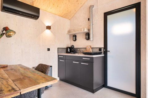 Angolo cottura compatto con dettagli in legno nella Nature house 'Barn' al campeggio Si-Es-An, Paesi Bassi.