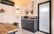 Angolo cottura compatto con dettagli in legno nella Nature house 'Barn' al campeggio Si-Es-An, Paesi Bassi.