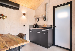 Angolo cottura compatto con dettagli in legno nella Nature house 'Barn' al campeggio Si-Es-An, Paesi Bassi.