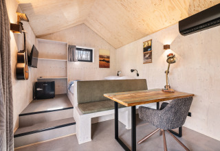 Interior of Nature house 'Barn' at Campsite Si-Es-An, Netherlands, with bed, desk, guitar, and wall art.