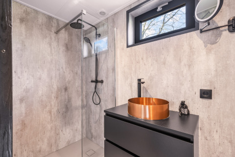 Baño moderno con lavabo de cobre y ducha tipo lluvia en Nature House 'Barn', camping Si-Es-An, Países Bajos.