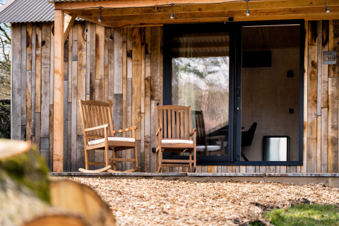 Casa de naturaleza 'Barn' en el camping Si-Es-An, Países Bajos, con dos sillas de madera en la veranda.